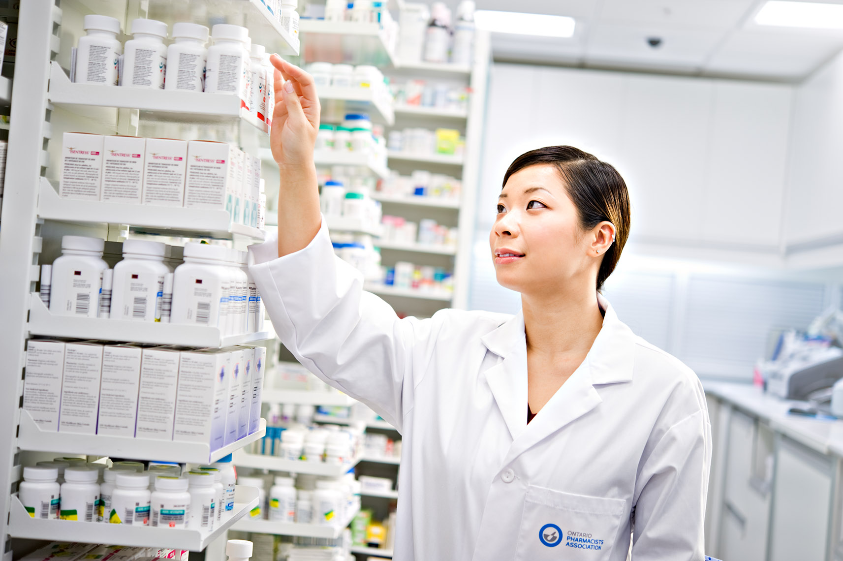 Toronto pharmacist reaching for drug on shelf for Ontario Pharmacists Association