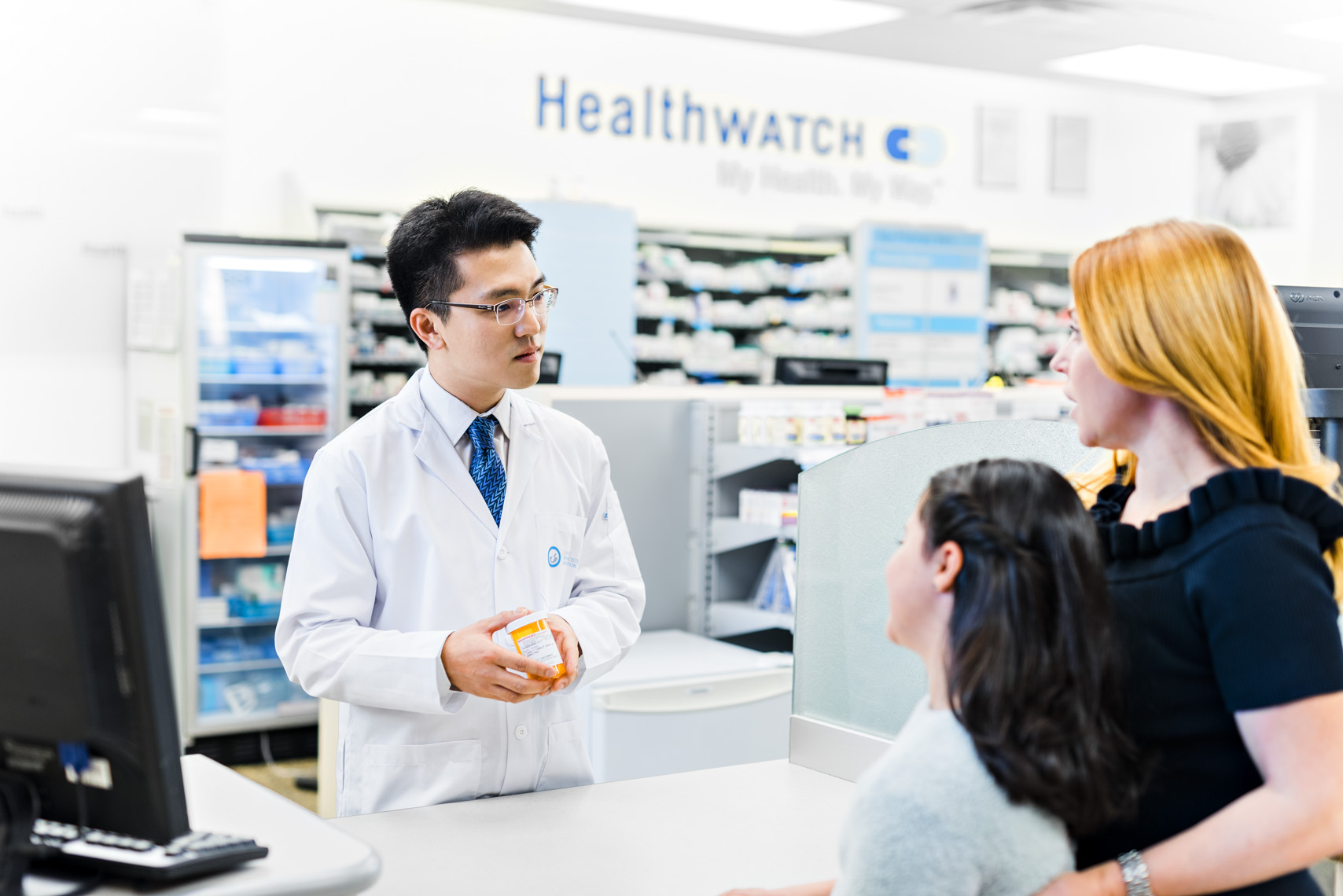 Male Toronto pharmacist listening to mother and daughter