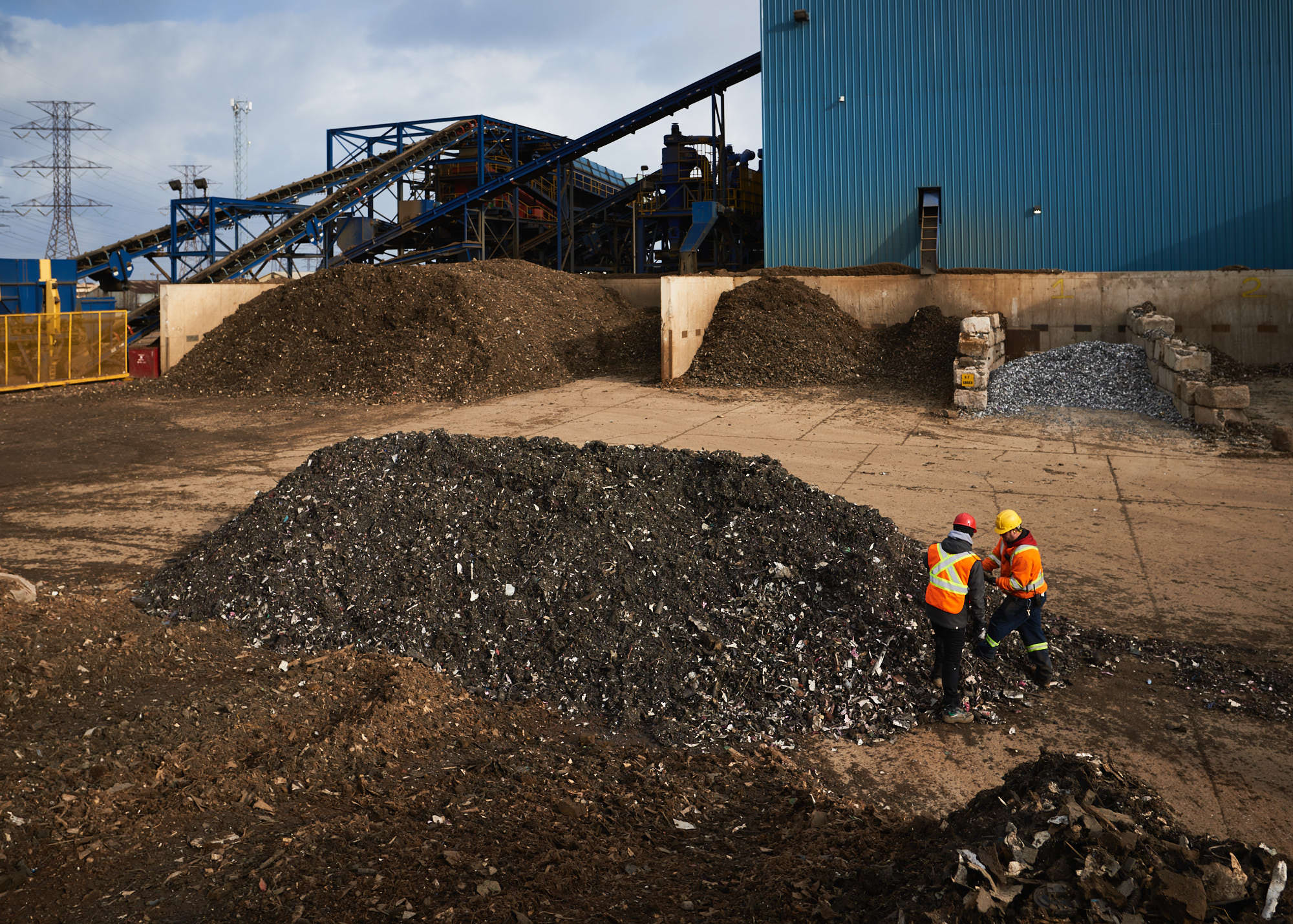 Overhead photograph of two male industrial workers discussing steel recycling outside manufacturing plant
