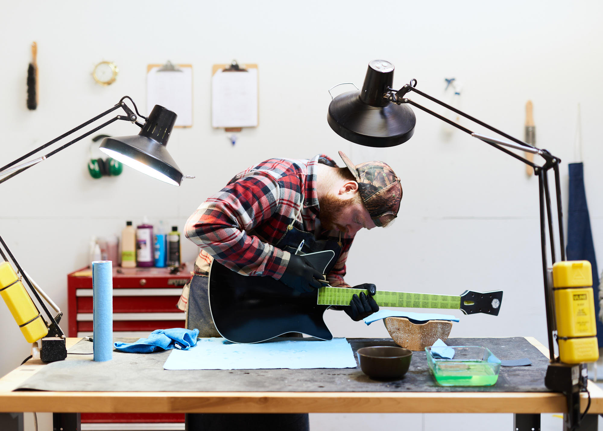Small business owner polishing guitar in studio