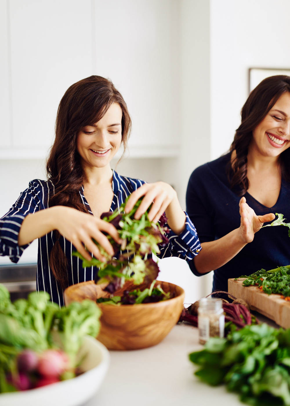 young-women-preparing-salad-in-kitchen